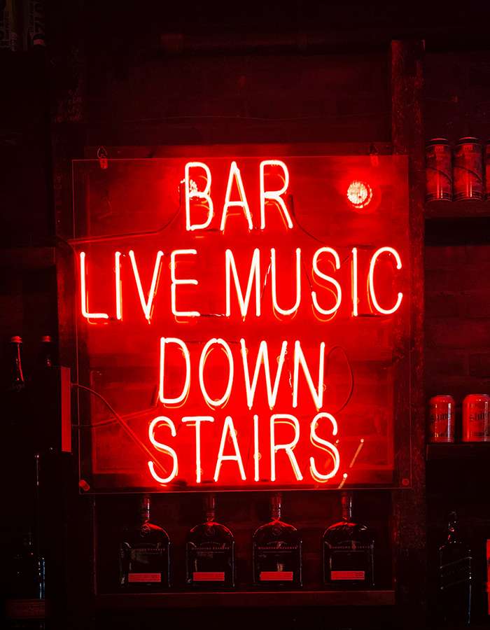 Ein Leuchtreklameschild mit der Aufschrift "Bar Live Music Down Stairs"